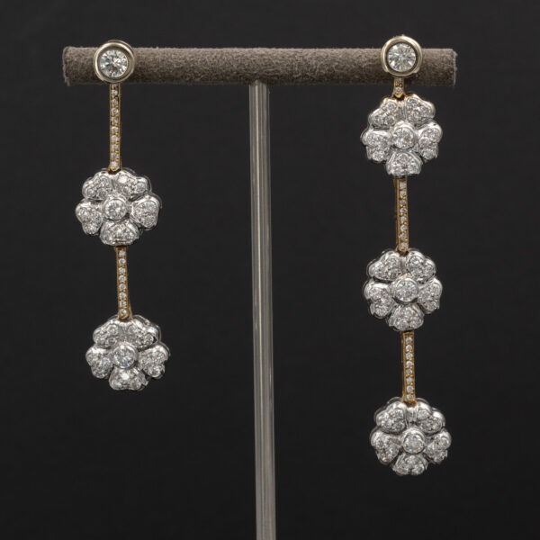 Dangle-FloralEarrings-Claris-A Diamond floral drop earrings in 18K white and yellow gold with asymmetric flower clusters and slender connecting lines by Claris-A.