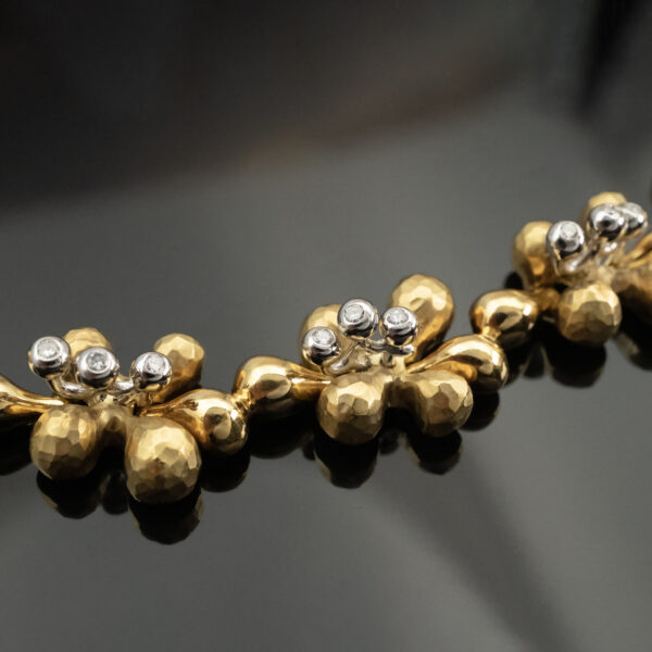 gold-diamond-floral-necklace-claris-a.jpg Gold and diamond floral necklace in 18K yellow gold with hammered petals, polished links, and alternating diamond-set and plain flowers by Claris-A.