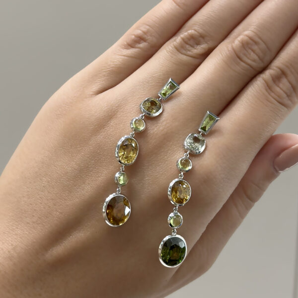 zircon-peridot-dangle-earrings-claris-a.jpg White gold earrings with alternating natural zircons and peridots arranged in a long articulated line for fluid movement.