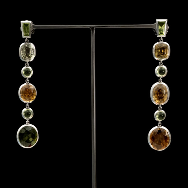 zircon-peridot-dangle-earrings-claris-a.jpg White gold earrings with alternating natural zircons and peridots arranged in a long articulated line for fluid movement.
