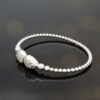 diamond-cuff-bracelet-18k-white-gold.jpg 18K white gold diamond cuff bracelet with articulated bead structure and teardrop diamond caps
