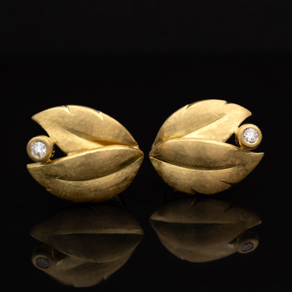 Hammered yellow gold leaf earrings with an open tip design, each set with a single diamond suspended between the curved terminals.