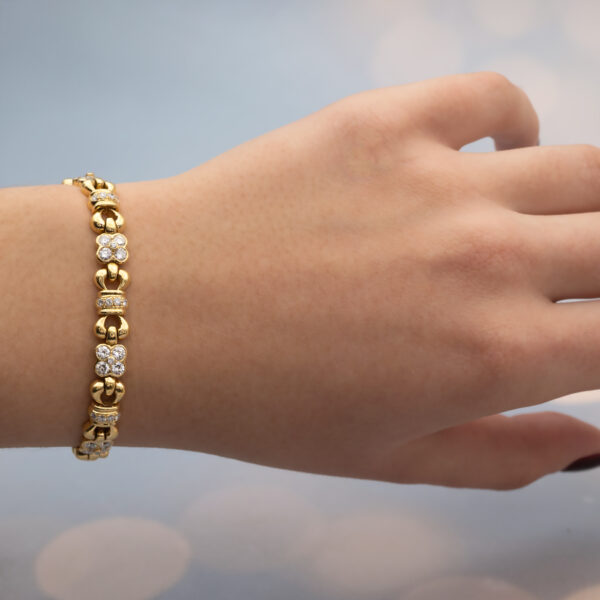 Diamond Floral Link Bracelet in 18K Yellow Gold Articulated 18K yellow gold bracelet with rounded links and raised floral motifs set with diamonds, forming a fluid, polished design.