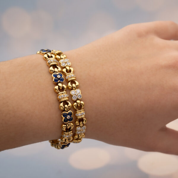 5718 Articulated 18K yellow gold bracelet with rounded links and raised floral motifs set with sapphires and diamonds in a fluid design.