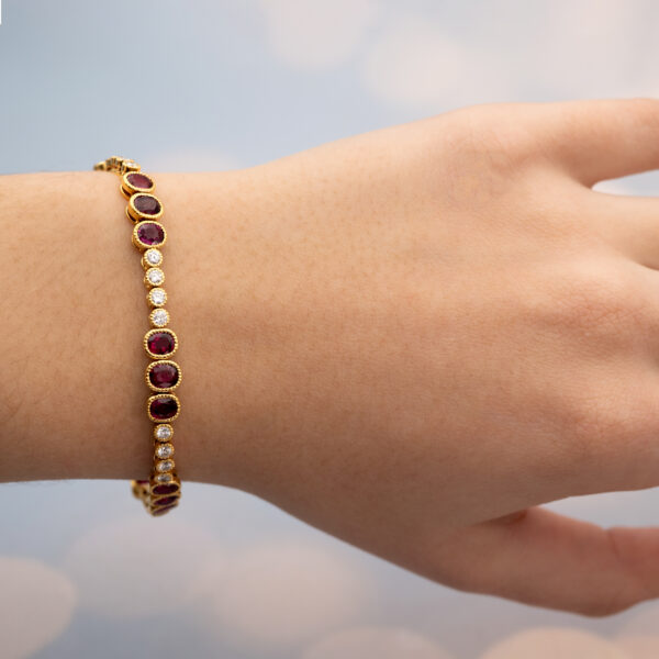 YellowGold_LinkBracelet_With_Ruby Articulated 18K yellow gold link bracelet set with rubies and diamonds, featuring sculptural geometric links arranged in a fluid line.