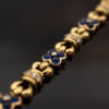 5741 Articulated 18K yellow gold bracelet with rounded links and raised floral motifs set with sapphires and diamonds in a fluid design.