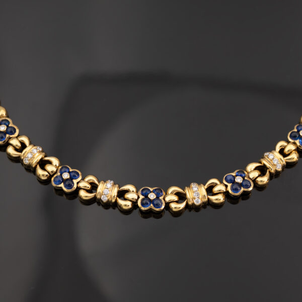 5744 Articulated 18K yellow gold bracelet with rounded links and raised floral motifs set with sapphires and diamonds in a fluid design.