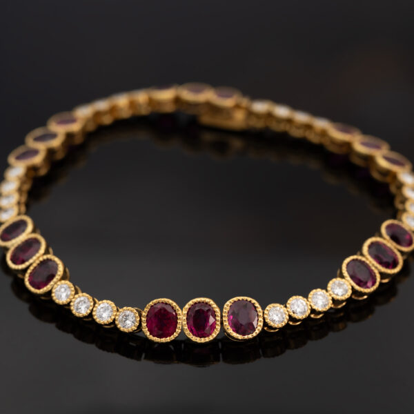 Articulated 18K yellow gold link bracelet set with rubies and diamonds, featuring sculptural geometric links arranged in a fluid line.