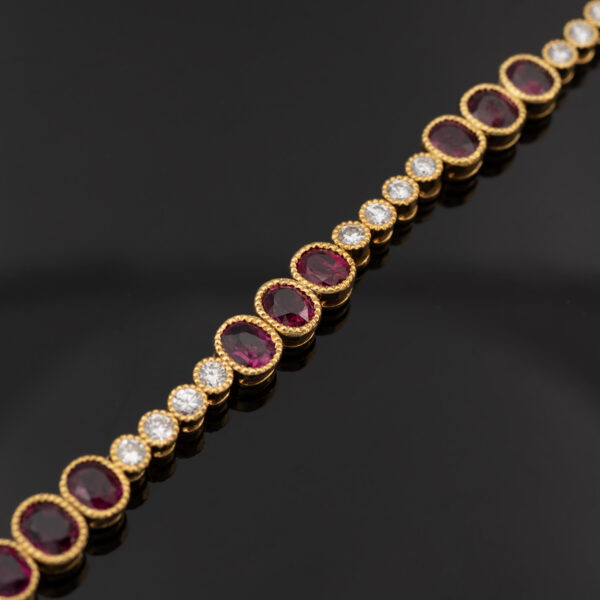 YellowGold_LinkBracelet_With_Ruby Articulated 18K yellow gold link bracelet set with rubies and diamonds, featuring sculptural geometric links arranged in a fluid line.
