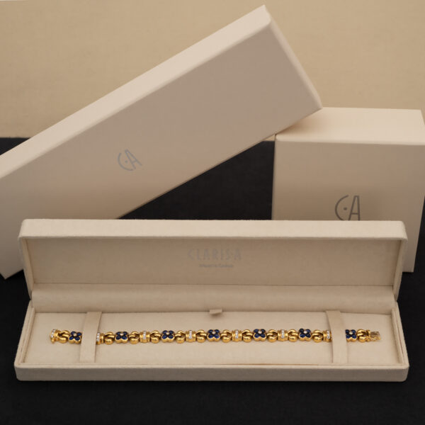 5780 Articulated 18K yellow gold bracelet with rounded links and raised floral motifs set with sapphires and diamonds in a fluid design.