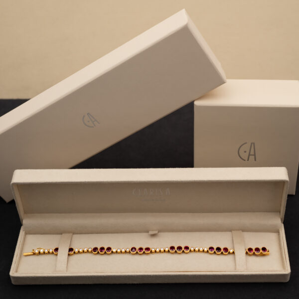 Box_ClarisA_LinkBracelet Articulated 18K yellow gold link bracelet set with rubies and diamonds, featuring sculptural geometric links arranged in a fluid line.