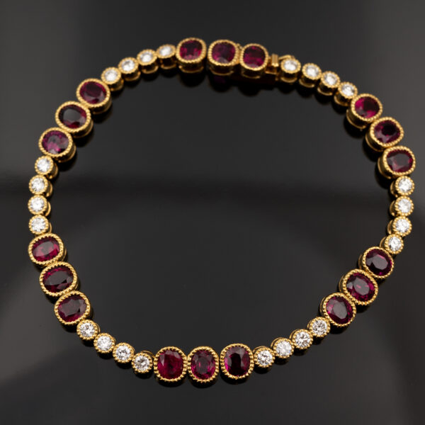Articulated 18K yellow gold link bracelet set with rubies and diamonds, featuring sculptural geometric links arranged in a fluid line.