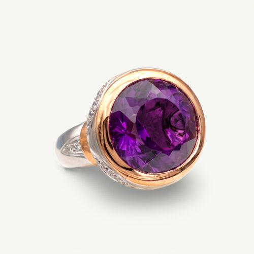 Claris-A-amethyst-diamond-cocktail-ring-white-yellow-gold-front 18K white and yellow gold cocktail ring with a large round purple amethyst in a yellow gold bezel, diamonds set along the gallery and shoulders, front view
