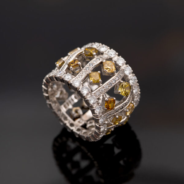 Wide 18K white gold ring with structured diamond-set bars and rows of white and fancy colored diamonds around the band