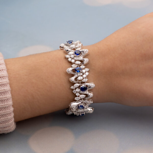 White gold bracelet with oval blue sapphires and diamond-set articulated links in a sculptural design