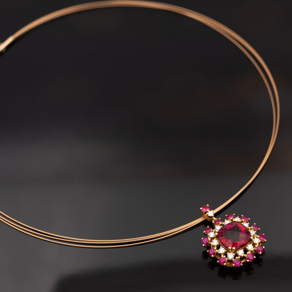 Floral Rubellite, Ruby & Diamond Cluster Pendant Necklace in Rose Gold Close-up of a 18K rose gold pendant necklace featuring a central rubellite surrounded by rubies and diamonds in a floral cluster design