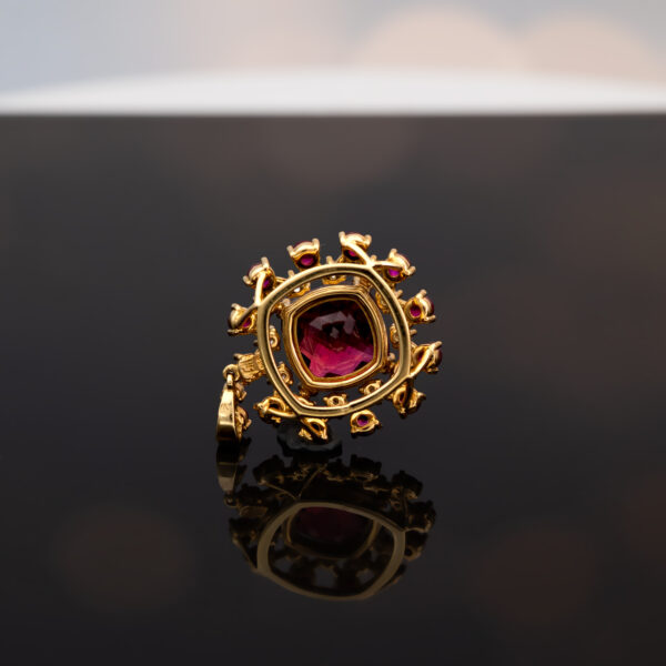Close-up of a 18K rose gold pendant necklace featuring a central rubellite surrounded by rubies and diamonds in a floral cluster design