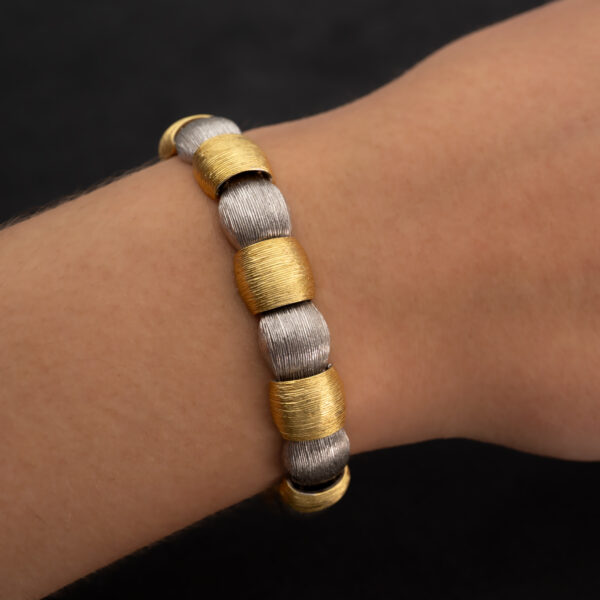 Italian Dual-Tone Gold Sculptural Bracelet Italian 18K white and yellow gold sculptural bracelet with textured engraved links, rounded connectors, and heart motifs on reverse.