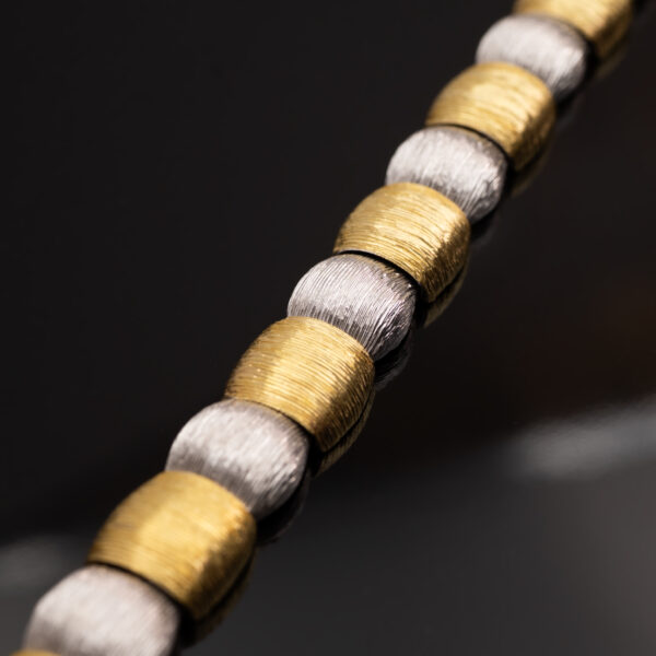 Italian Dual-Tone Gold Sculptural Bracelet Italian 18K white and yellow gold sculptural bracelet with textured engraved links, rounded connectors, and heart motifs on reverse.