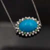 Turquoise Tsavorite Diamond Sunburst Necklace in White Gold White gold pendant necklace with oval turquoise centre surrounded by tsavorites and diamonds in a floral sunburst motif.